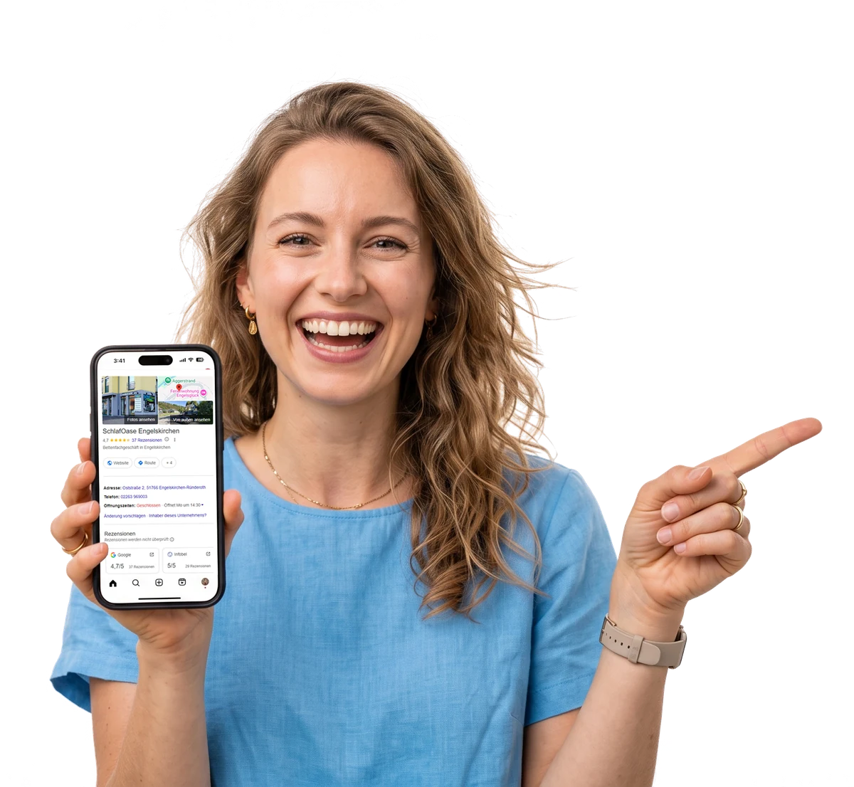Lachende Frau hält ein Smartphone mit dem Google-Profil der SchlafOase Engelskirchen und zeigt mit dem Finger darauf