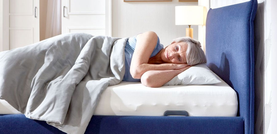 Frau liegt im Bett mit Liftrahmen